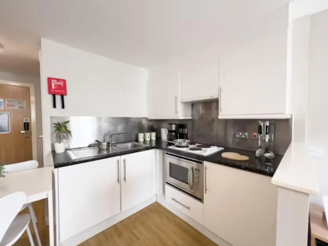 White cabinets sink stove microwave kitchen area at Panmure Court in Edinburgh Student Accommodation