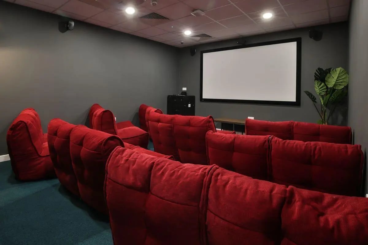 Red beanbag chairs facing a movie screen cinema room at Ocean View in Falmouth Student Accommodation