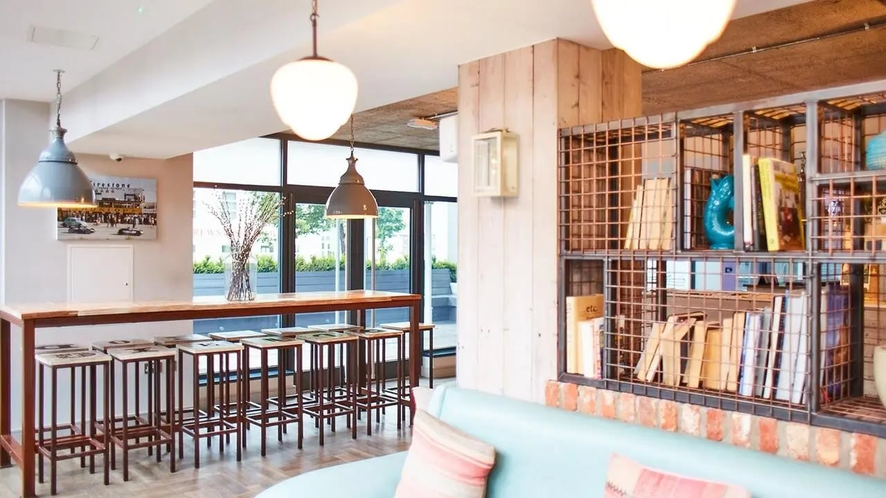 Wooden bar with stools bookshelf with books lounge area at Canvas The Parade in Cardiff Student Accommodation