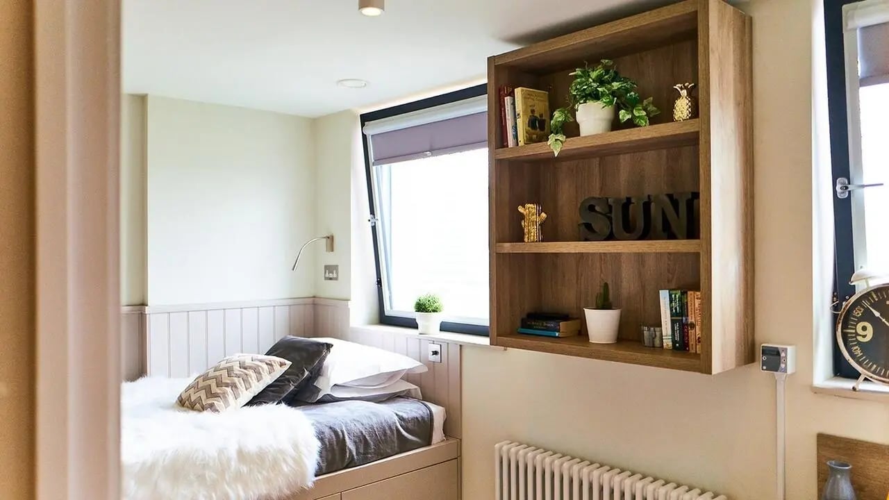 Bed with pillows and fluffy throw wooden shelf bedroom at Canvas The Parade in Cardiff Student Accommodation