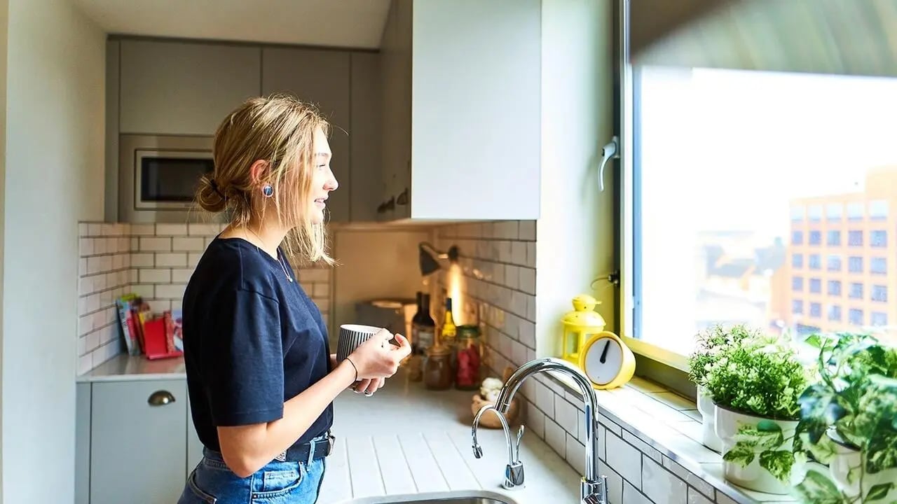 Young woman holding mug in a modern kitchen at Canvas The Parade in Cardiff Student Accommodation