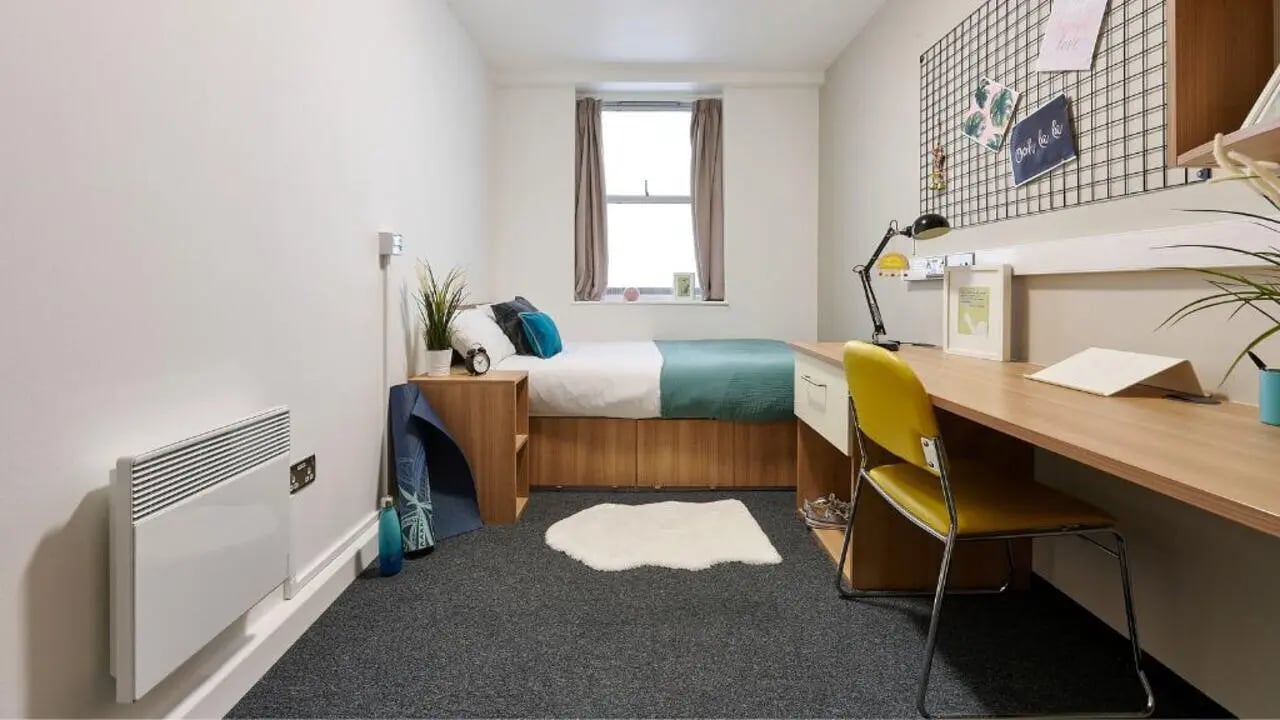 Bed heater desk and yellow chair bedroom at Northernhay House in Exeter Student Accommodation