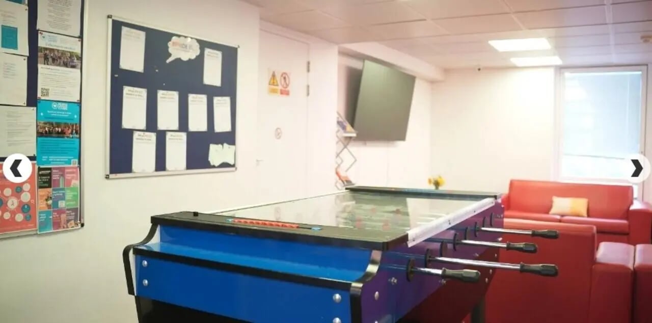 Foosball table red couches bulletin board common area at Dinwiddy House in London Student Accommodation