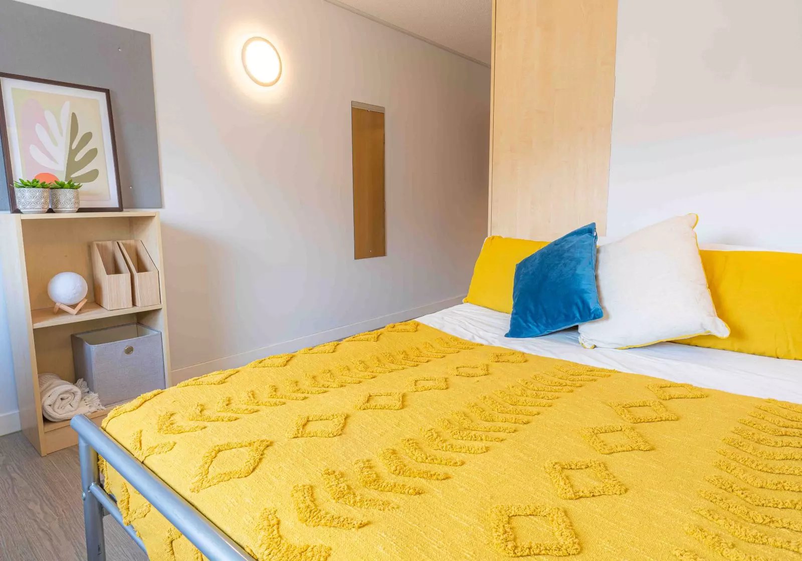 Yellow patterned bed with blue white yellow pillows bedroom at iQ Arkwright House in Bradford Student Accommodation