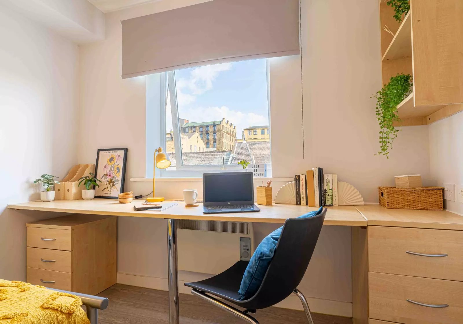 Desk with laptop lamp books and plants study area at iQ Arkwright House in Bradford Student Accommodation