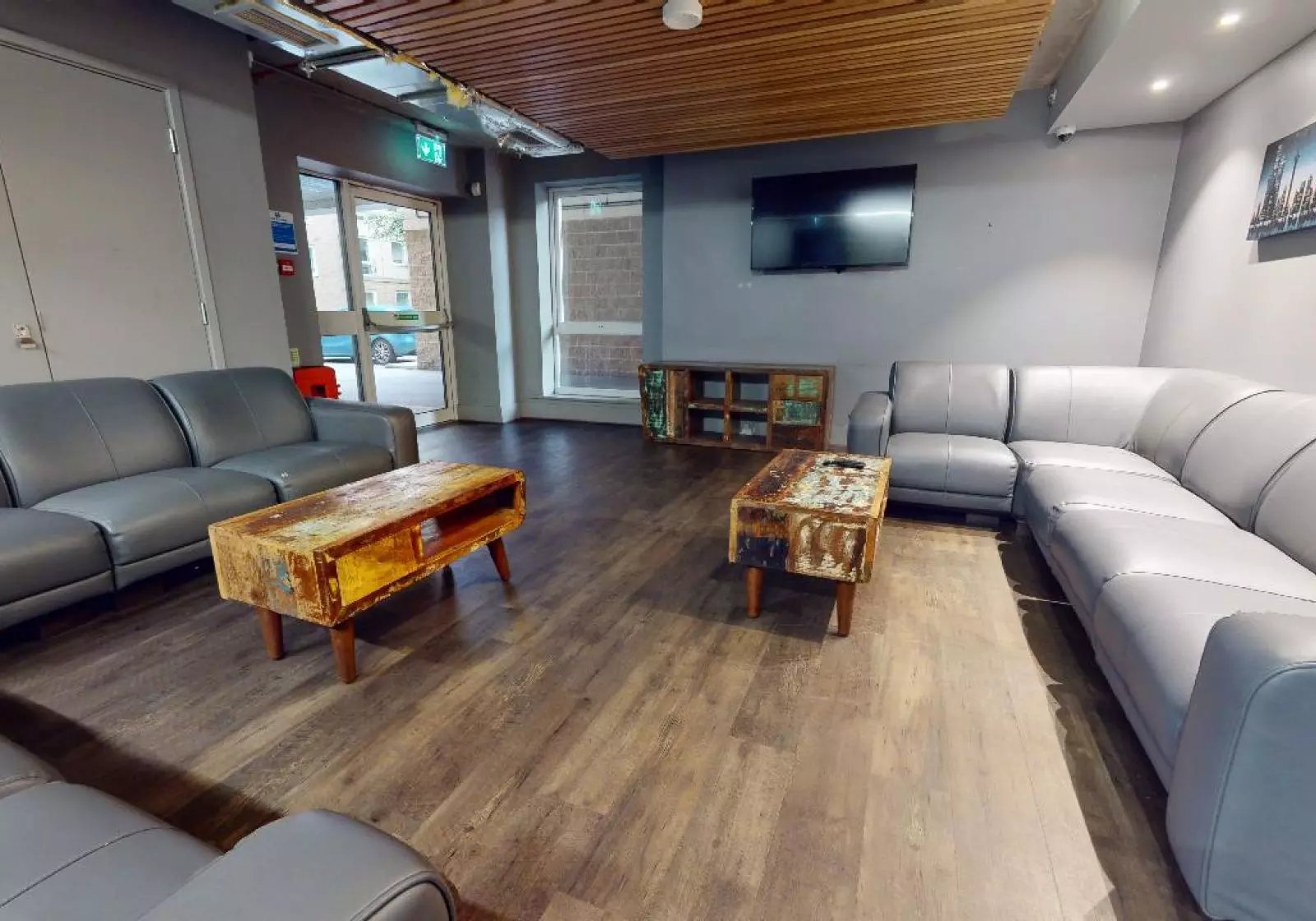 Grey sofas two rustic tables television living room at iQ Arkwright House in Bradford Student Accommodation