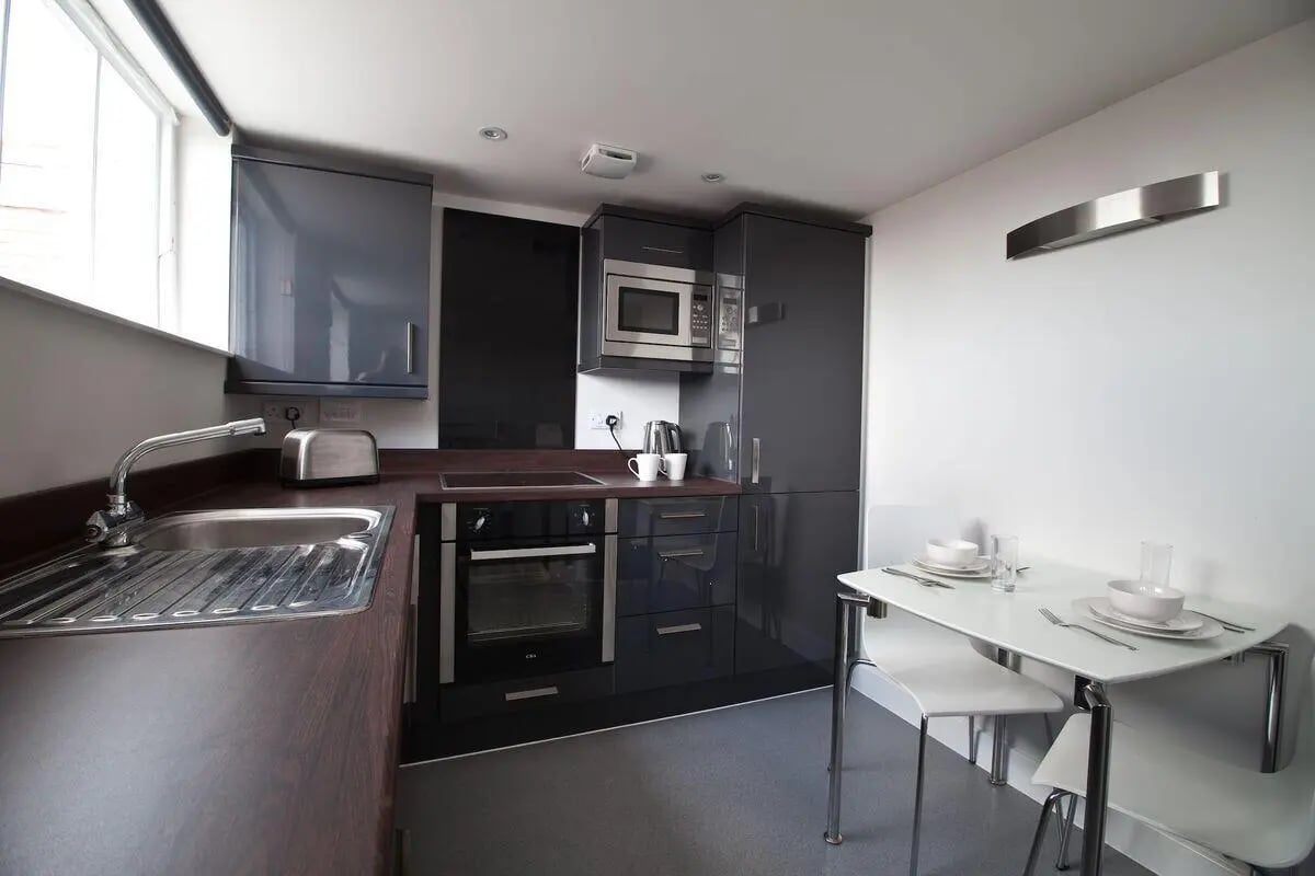 Sink oven microwave toaster and dining table kitchen at Dean Clarke Lofts in Exeter Student Accommodation