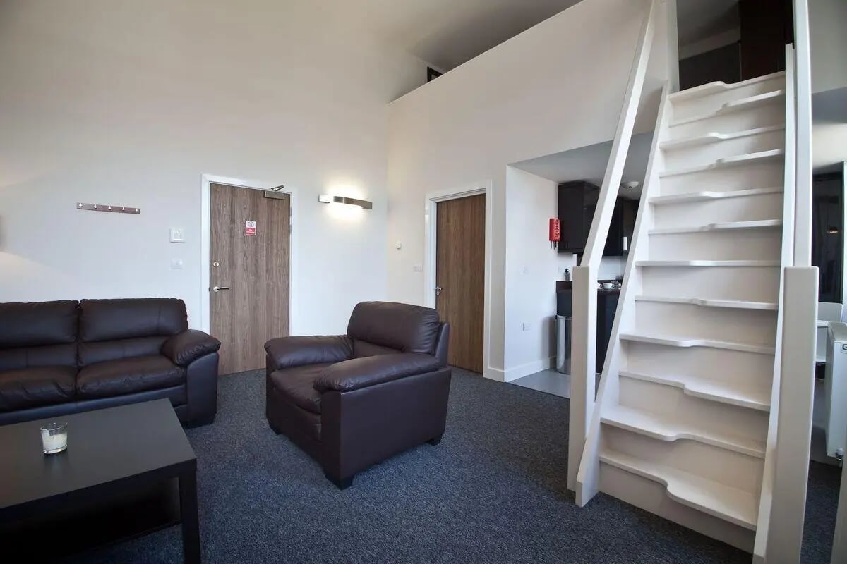 Leather sofas chairs coffee table stairs living room at Dean Clarke Lofts in Exeter Student Accommodation