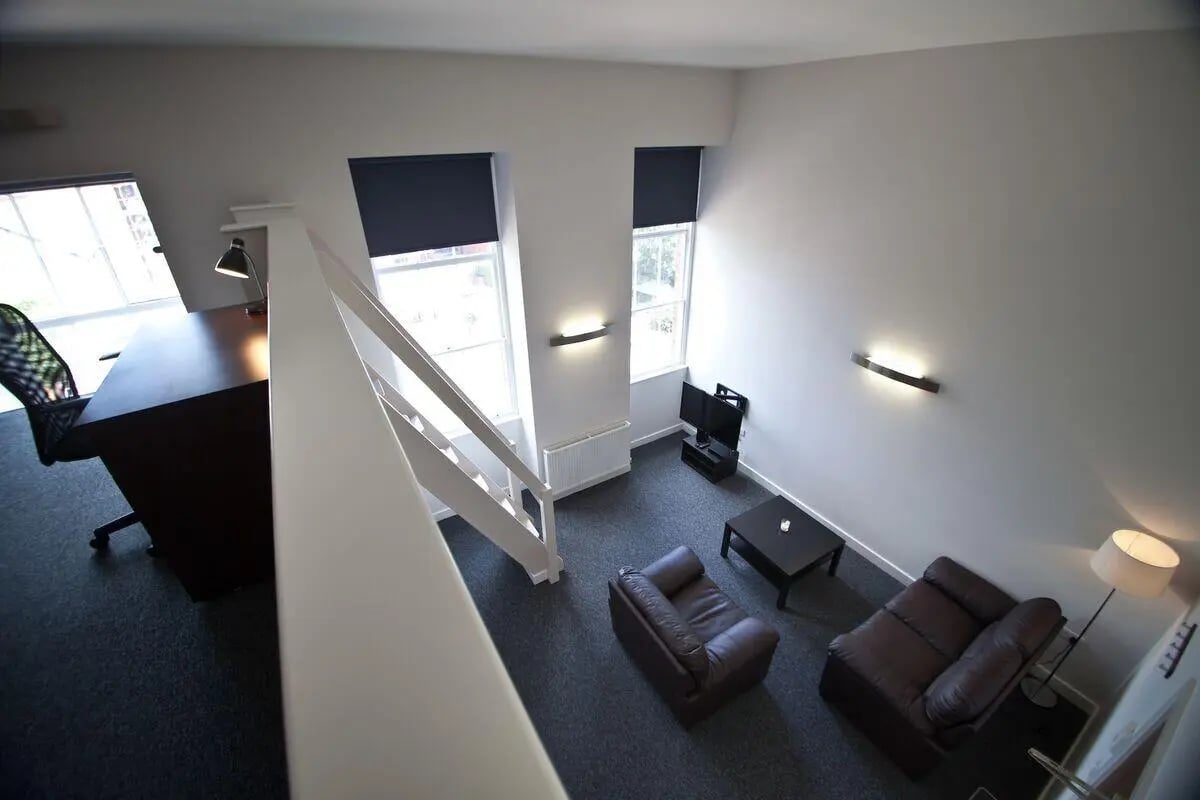 Desk chair desk staircase couches television living room at Dean Clarke Lofts in Exeter Student Accommodation