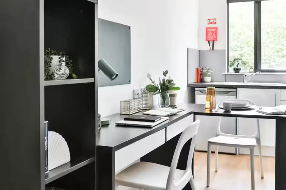 Desk bookshelf plants kitchen living area at Hayward House in Liverpool Student Accommodation