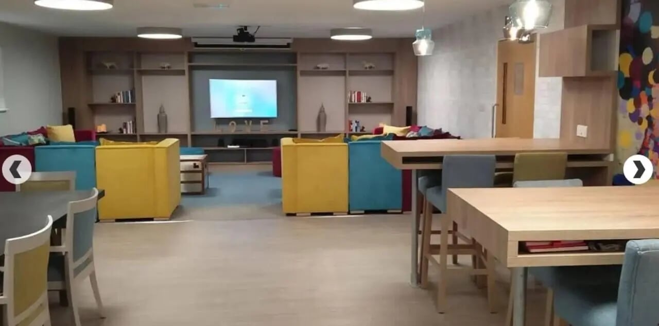 Seating area with TV tables and chairs communal space at Lilian Knowles House in London Student Accommodation