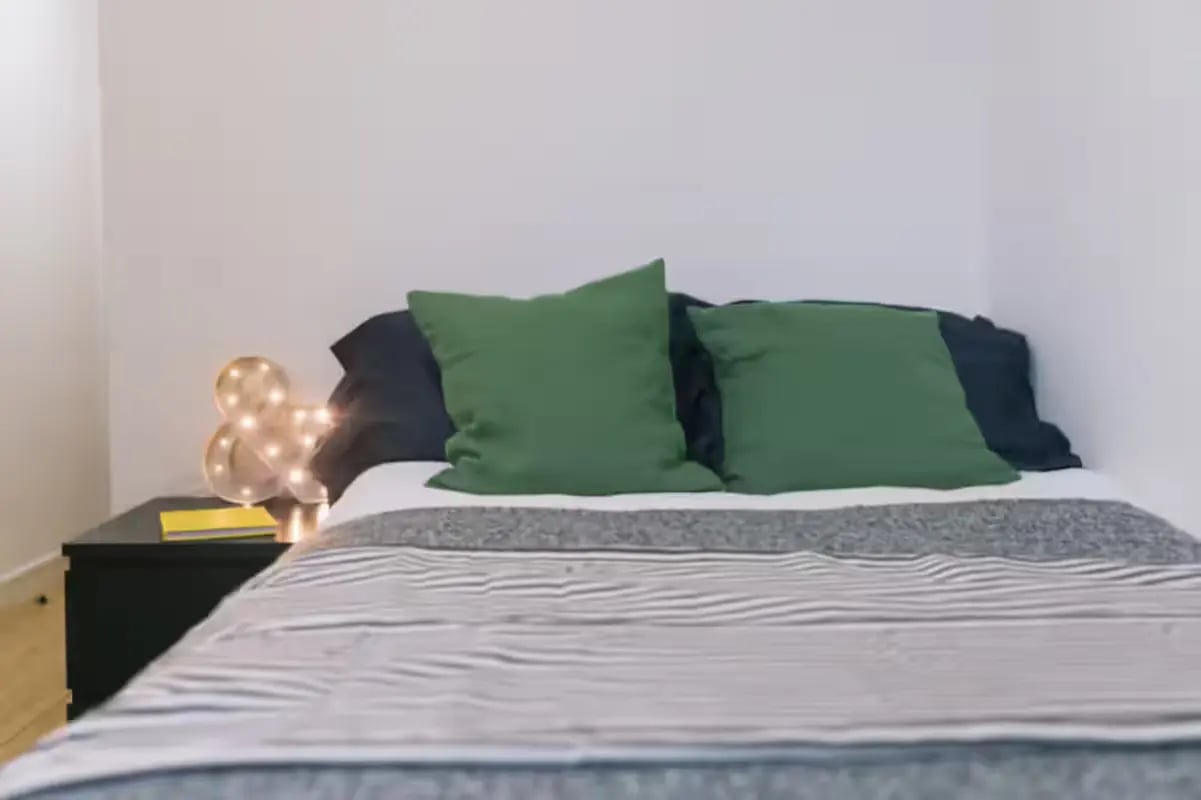 Bed with green pillows and bedside lamp bedroom at Chatham Lodge in Liverpool Student Accommodation