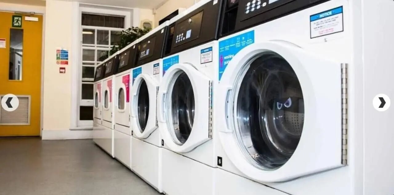 Row of white washing machines laundry area at Alliance House in London Student Accommodation