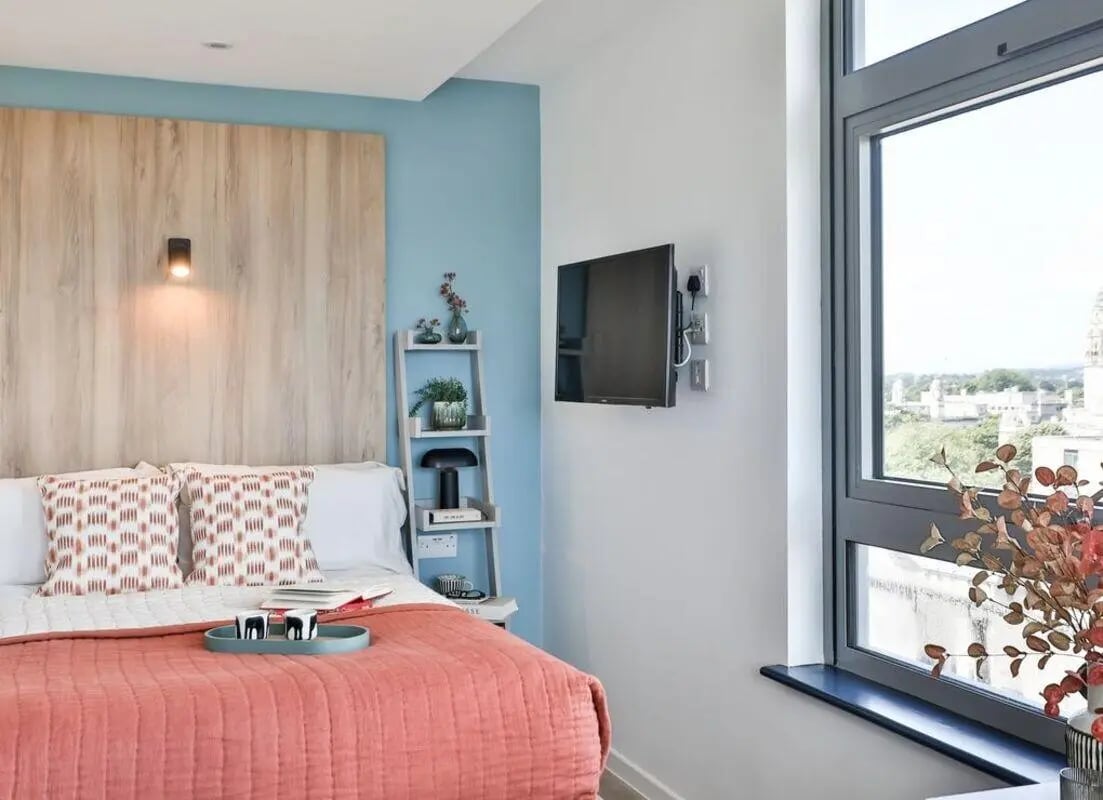 Bed with patterned pillows and coral blanket Bedroom at Summit House in Cardiff Student Accommodation