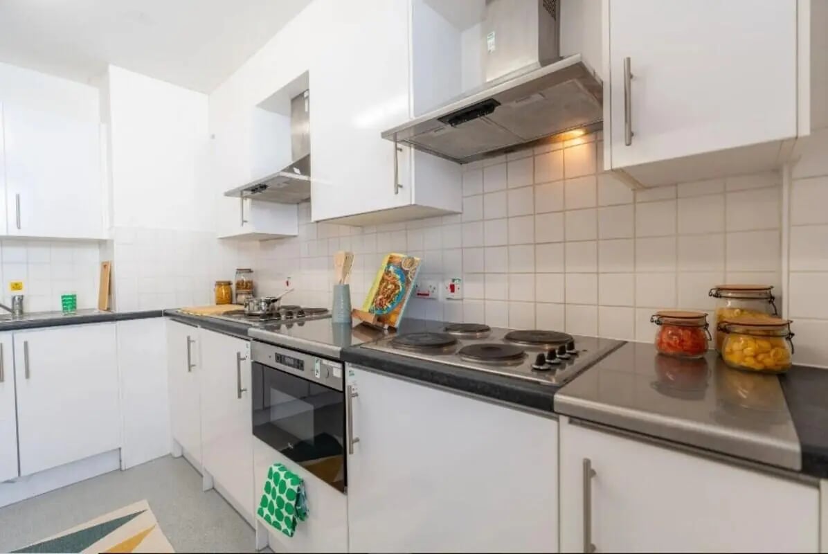 White kitchen cabinets electric stove jars of food kitchen at The Craft Building in London Student Accommodation