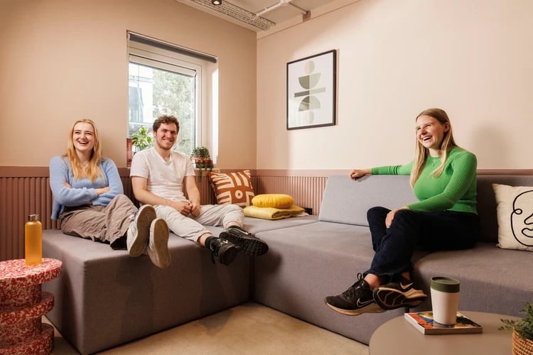 Students lounging on sectional sofa artwork and plants living room at The Bridge House in Edinburgh Student Accommodation