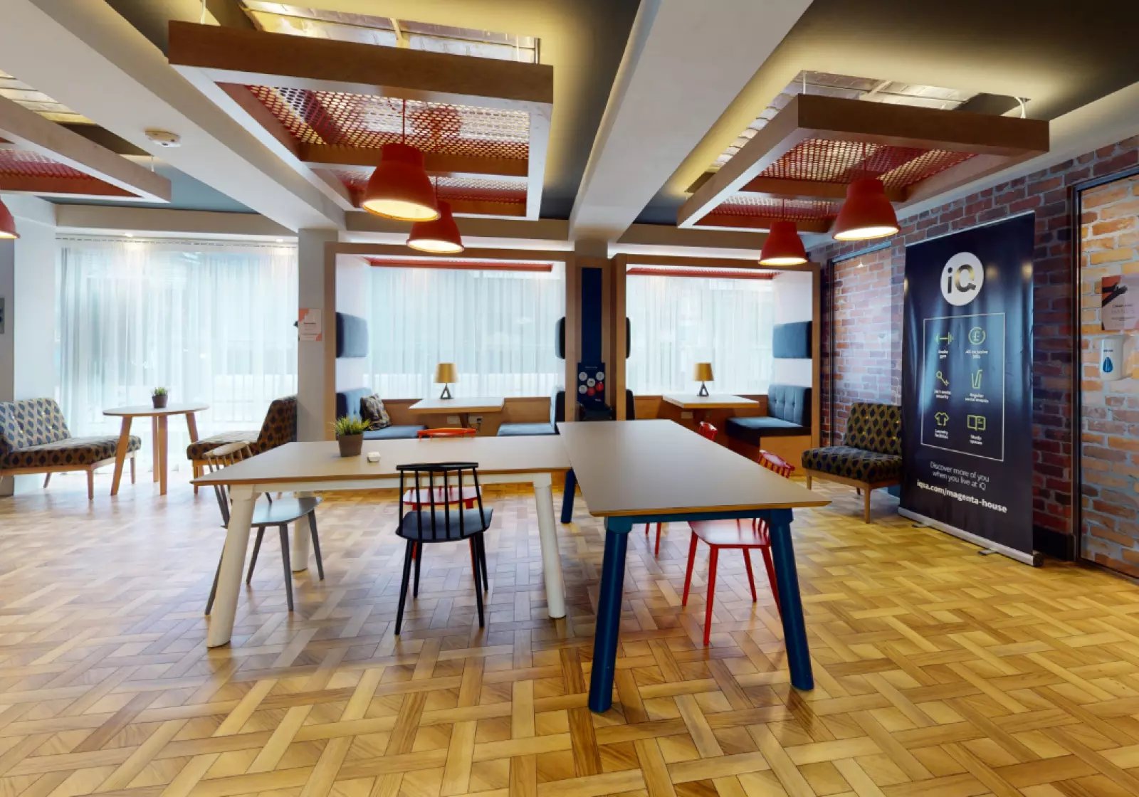 Communal tables and chairs with seating booths living room at iQ Magenta House in London Student Accommodation