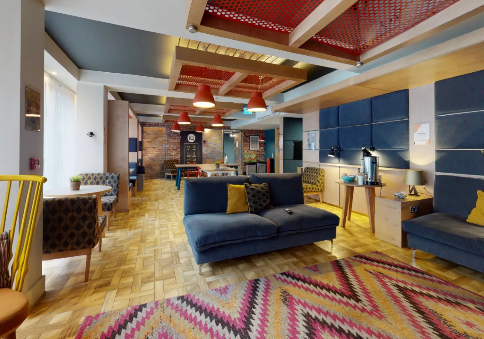 Blue sofa colourful rug brick wall communal area at iQ Magenta House in London Student Accommodation