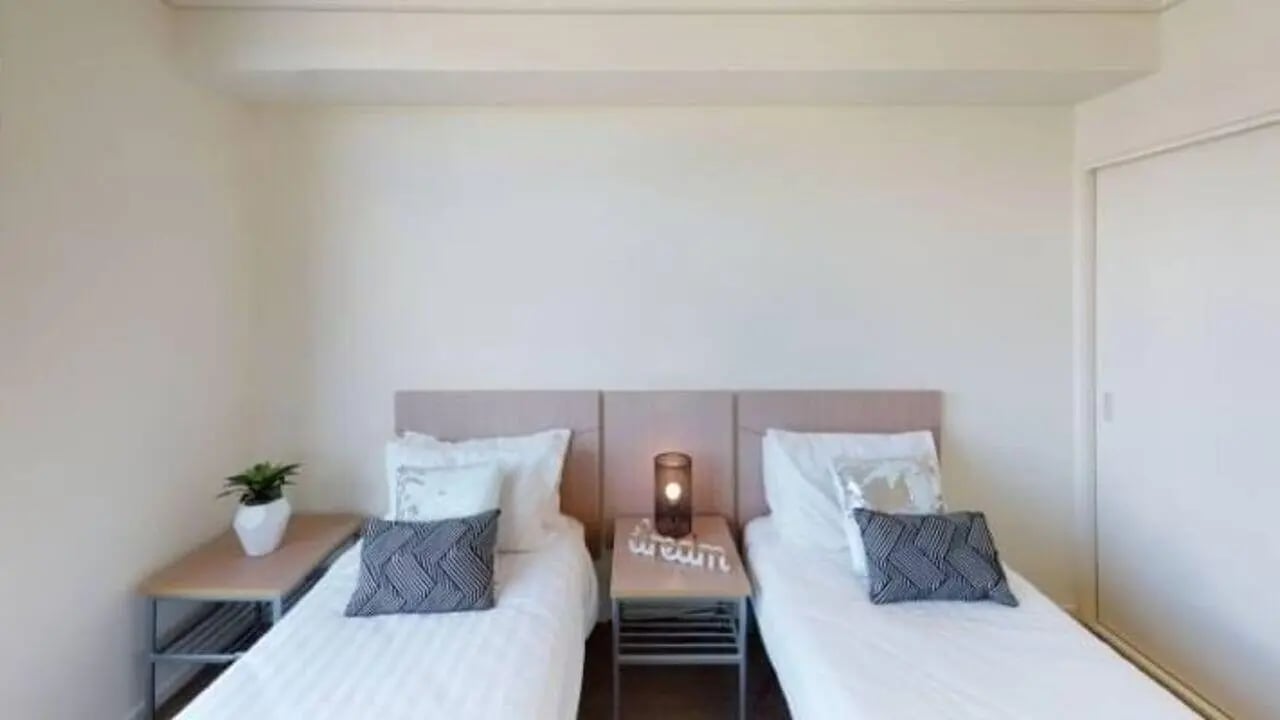 Two beds bedside tables plant and lamp bedroom at Student Living - 800 Swanston in Melbourne Student Accommodation
