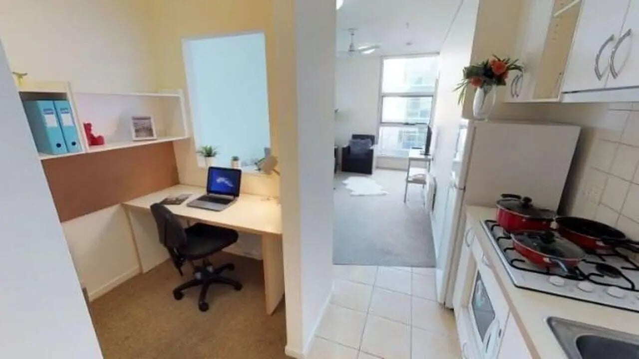 Desk laptop chair shelves kitchen living room exterior at Student Living - 800 Swanston in Melbourne Student Accommodation
