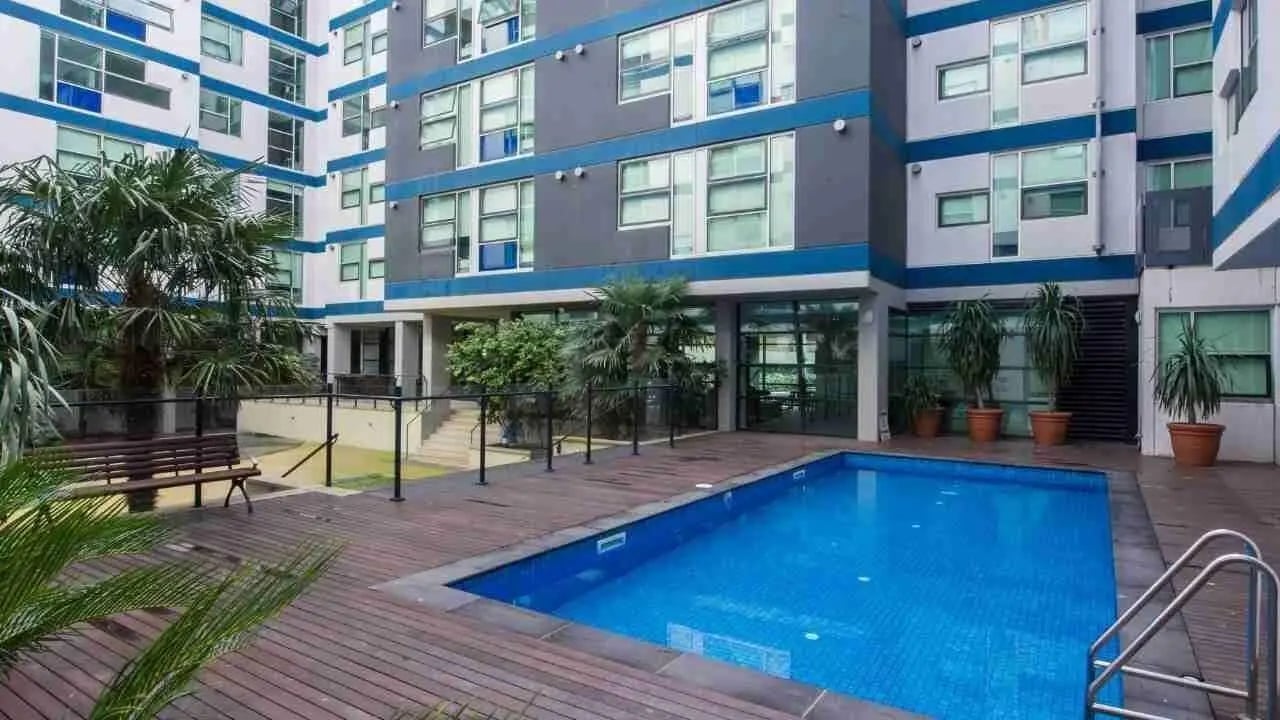 Pool deck with bench and palm trees exterior at Student Living - 800 Swanston in Melbourne Student Accommodation