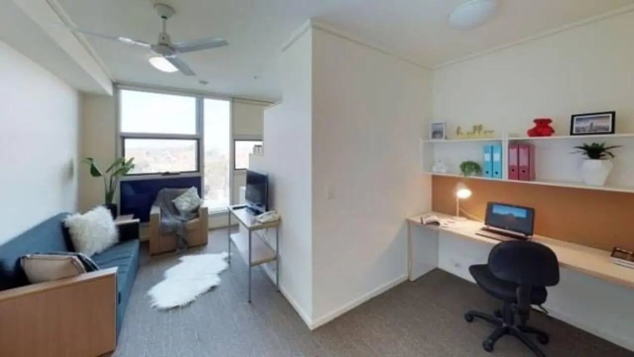Sofa chair desk computer and shelves living room at Student Living - 800 Swanston in Melbourne Student Accommodation