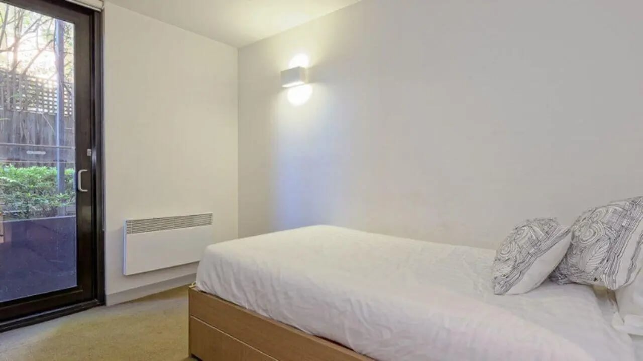 Bed with pillows wall heater glass door bedroom at Student Living on Riversdale in Melbourne Student Accommodation