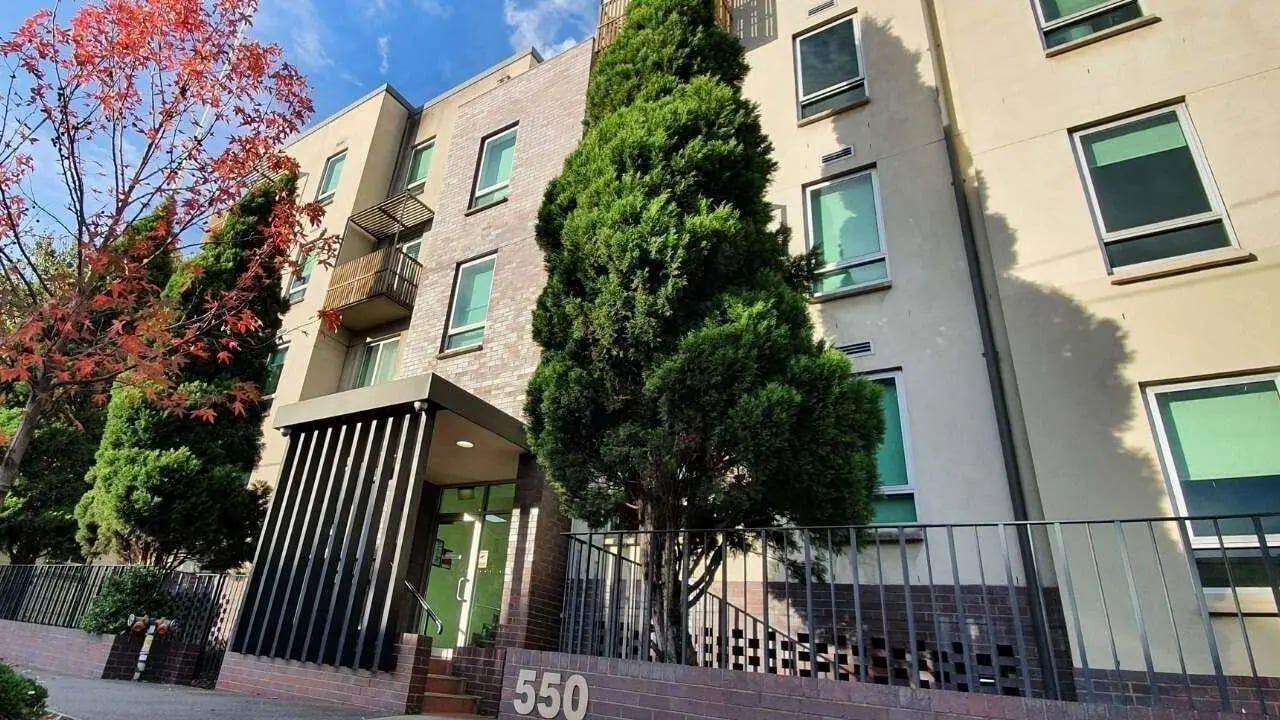 Apartment building entrance with trees and balcony exterior at Student Living - 550 Lygon in Melbourne Student Accommodation