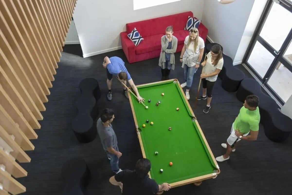 Students playing pool near red sofa communal area at ECU Village Joondalup in Perth Student Accommodation