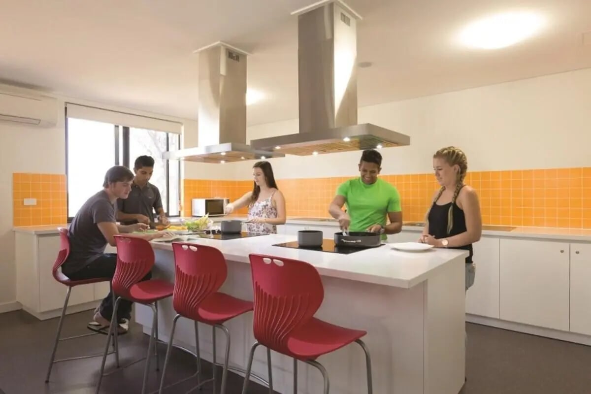 Students cooking at island with red bar stools kitchen at ECU Village Joondalup in Perth Student Accommodation