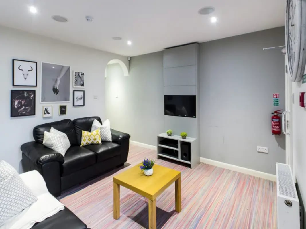 Black sofa tv and yellow coffee table living room at 210 Cauldon Road in Stoke-On-Trent Student Accommodation