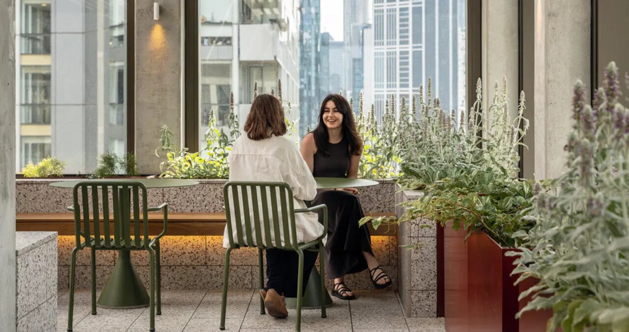 Two women sitting at tables with plants exterior at Iglu Melbourne Central in Melbourne Student Accommodation
