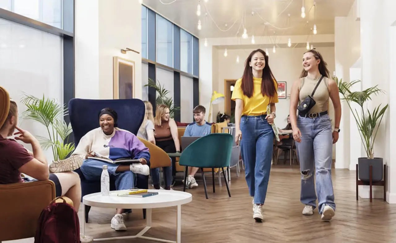 Students relaxing and walking in common area living room at The Plaza in Leeds Student Accommodation