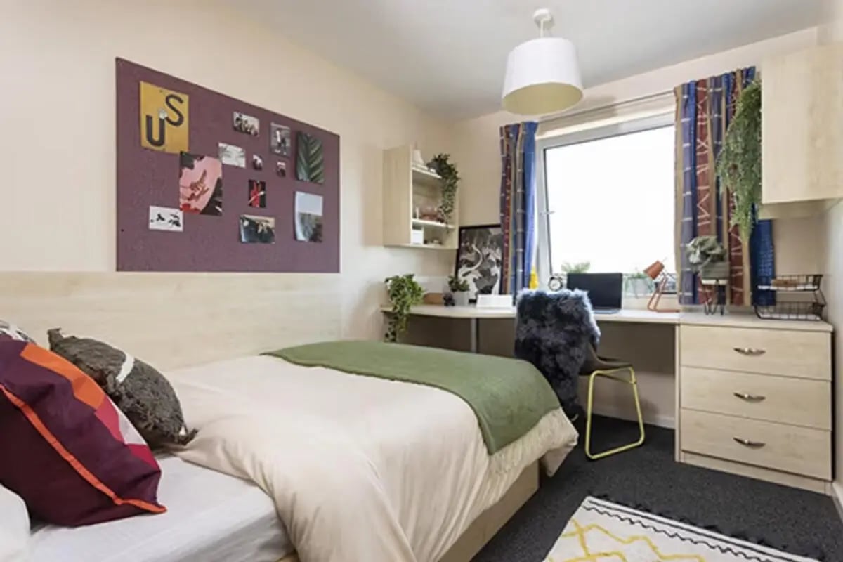 Bed desk corkboard and pillows bedroom at The Plaza in Leeds Student Accommodation