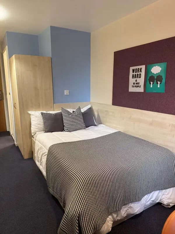 Bed wardrobe posters and blue wall bedroom at The Plaza in Leeds Student Accommodation
