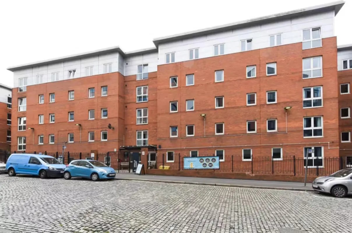 Brick building with cars and cobblestone street exterior at Apollo Court in Liverpool Student Accommodation