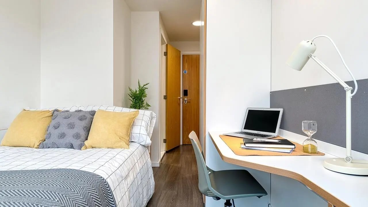 Bed desk lamp laptop notebooks hourglass study bedroom at Collegiate Merlin Heights in Leicester Student Accommodation