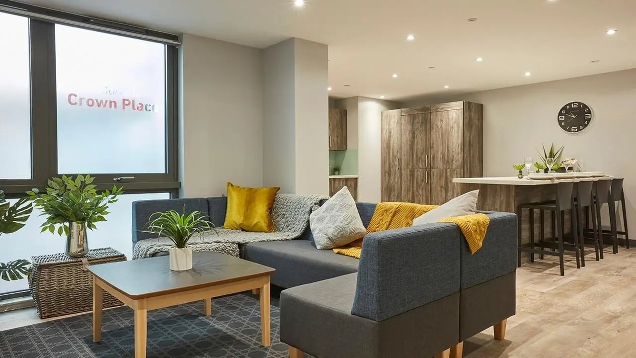 Grey sectional sofa wood table kitchen living room at Collegiate Crown Place Norwich in Norwich Student Accommodation