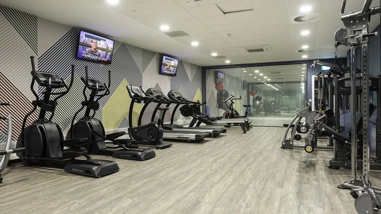 Cardio machines weight machines TVs patterned wall gym interior at Collegiate Crown Place Norwich in Norwich Student Accommodation