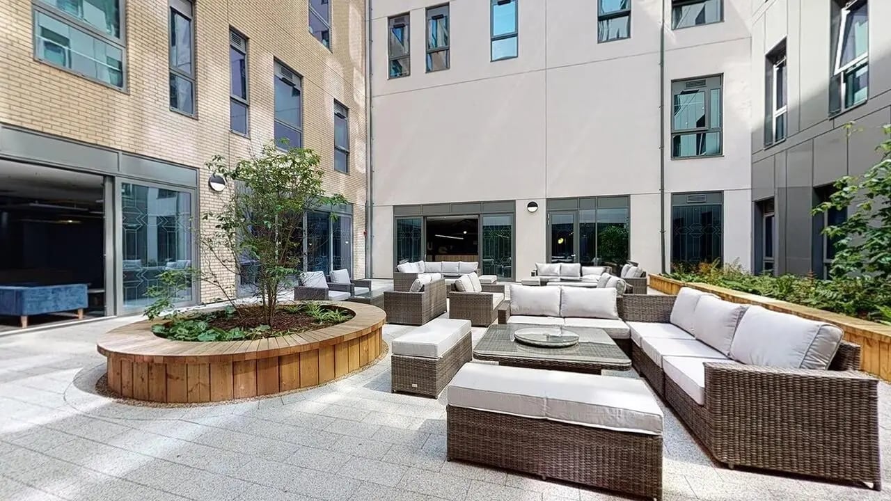 Courtyard with wicker sofas and wooden planter exterior at Collegiate Crown Place Norwich in Norwich Student Accommodation