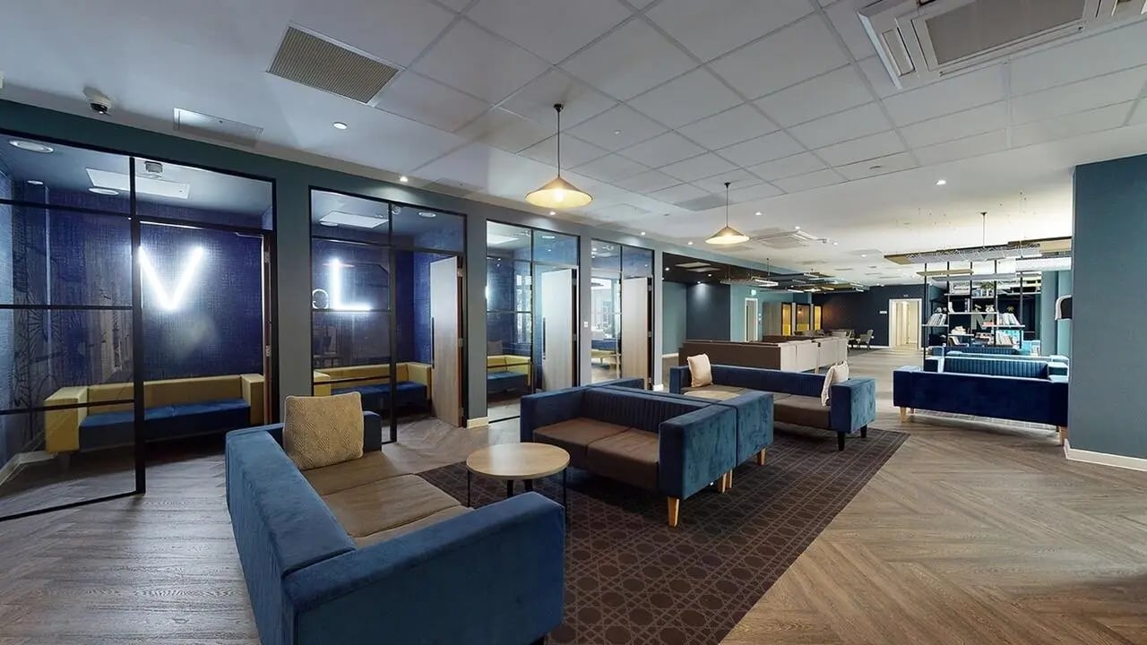 Blue sofas glass rooms illuminated letters common area at Collegiate Crown Place Norwich in Norwich Student Accommodation