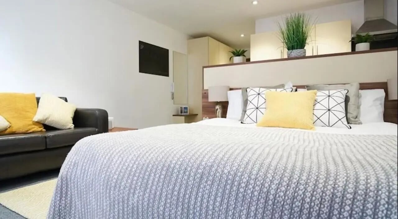 Bed with cushions sofa cabinets and plants bedroom at Windsor Court in Liverpool Student Accommodation