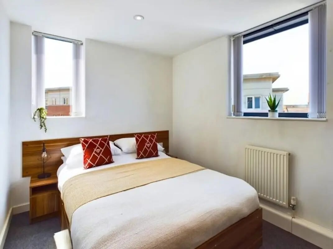 Bed with red pillows bedside table lamp bedroom at Windsor Court in Liverpool Student Accommodation