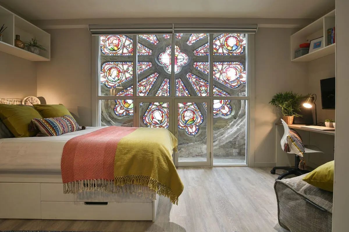 Bed desk and window with stained glass bedroom at The Chapel in Manchester Student Accommodation