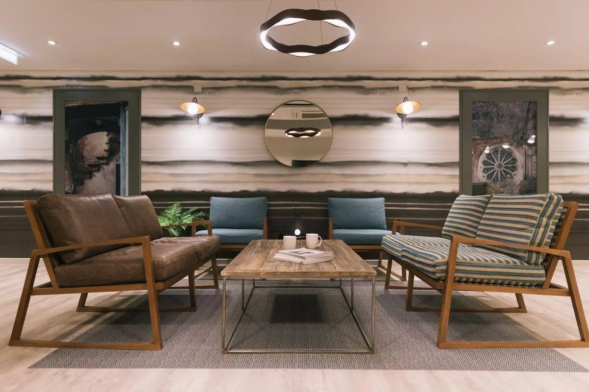 Sofa armchairs coffee table round mirror living room at The Chapel in Manchester Student Accommodation