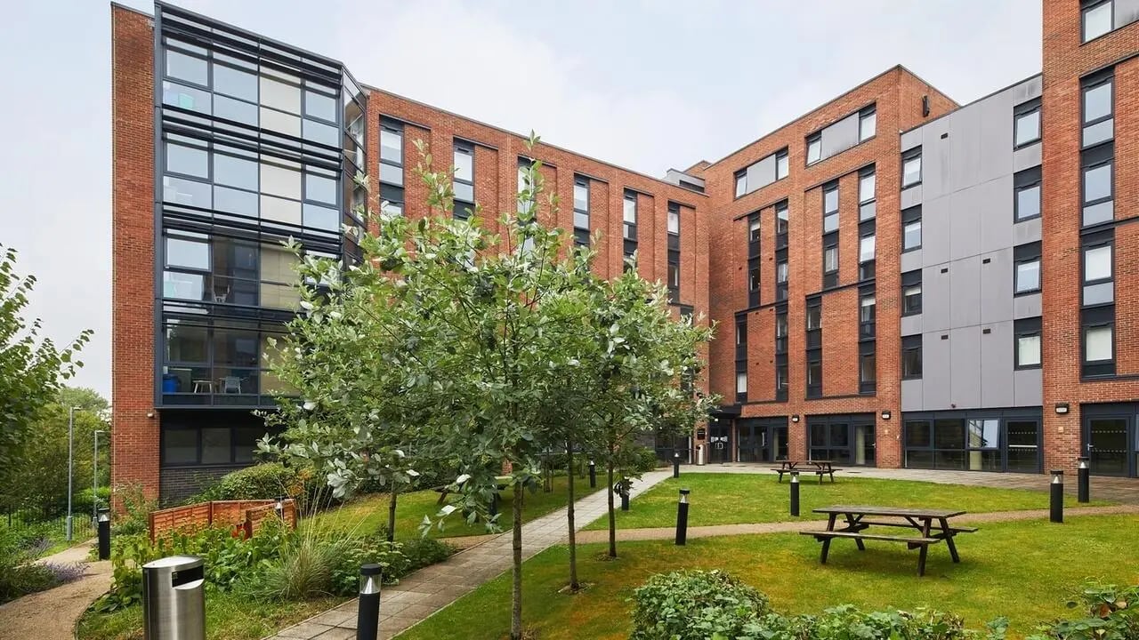 Modern brick building with trees and picnic tables exterior at Collegiate Riverside Way Winchester in Winchester Student Accommodation