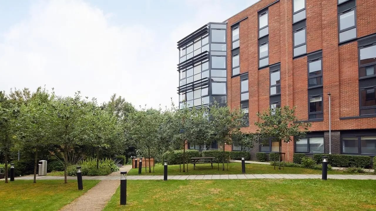 Brick building with modern glass facade green lawn exterior at Collegiate Riverside Way Winchester in Winchester Student Accommodation