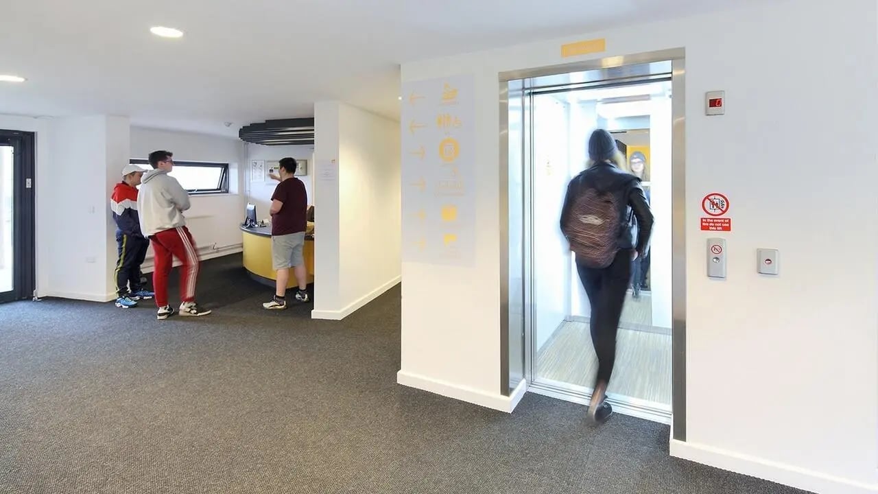 Students by reception and elevator interior at Collegiate Riverside Way Winchester in Winchester Student Accommodation