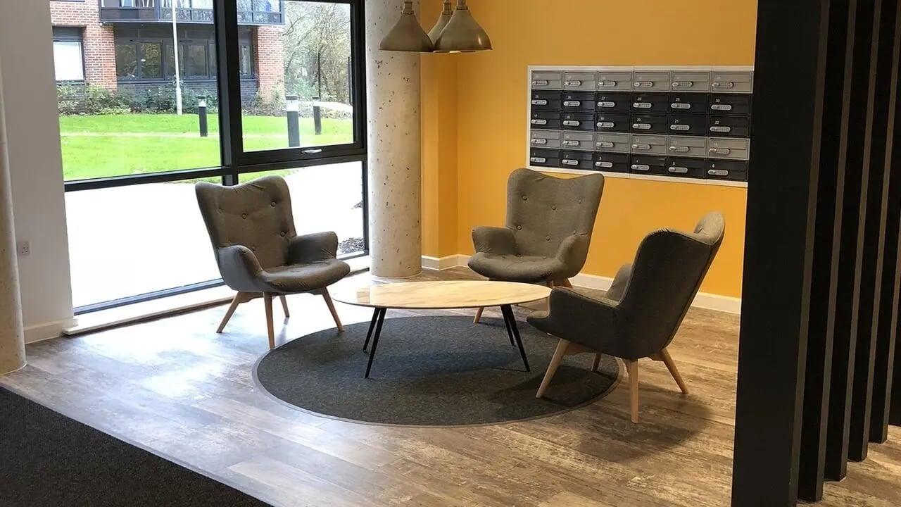 Three grey chairs surrounding oval coffee table seating area at Collegiate Riverside Way Winchester in Winchester Student Accommodation