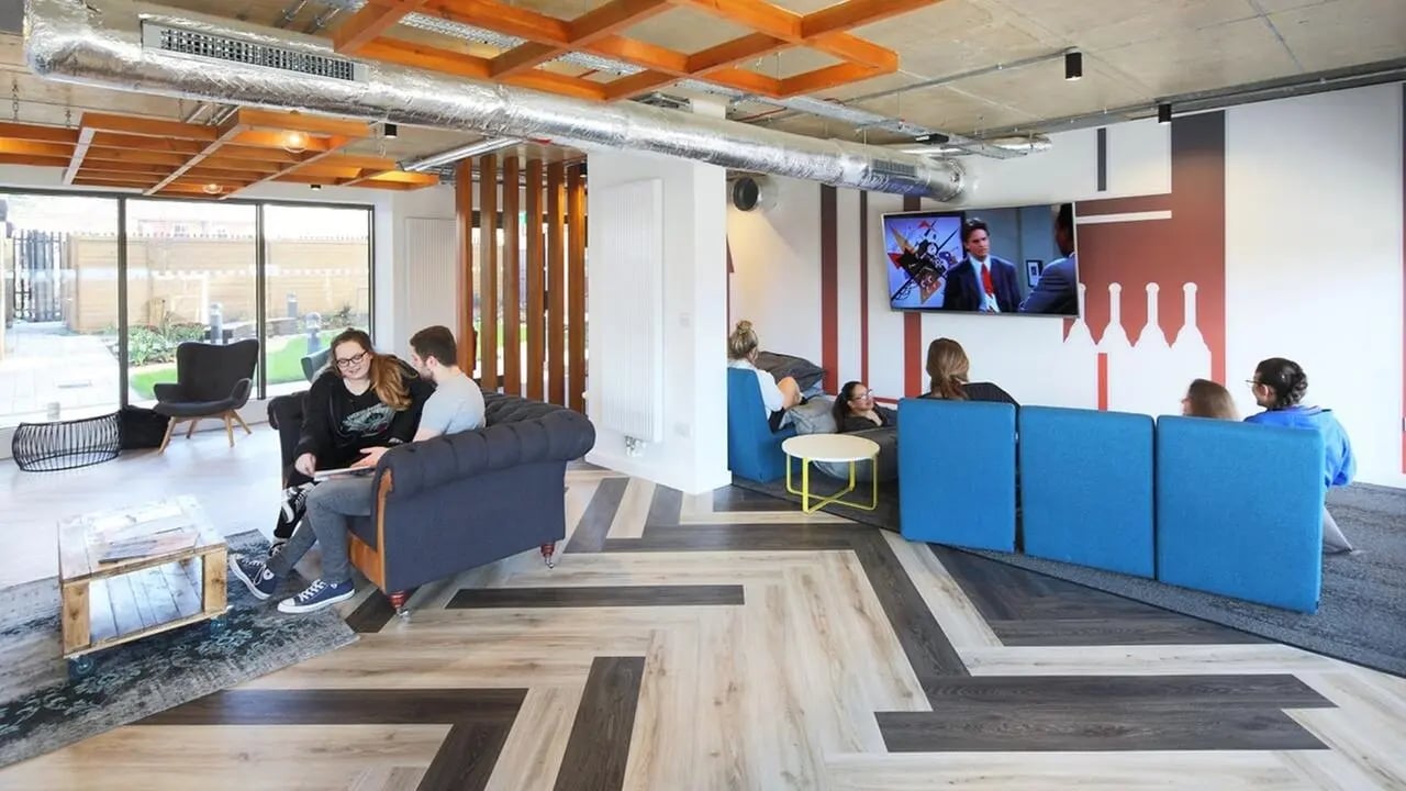 People relaxing on sofas watching TV living room at Collegiate Cathedral Point in Winchester Student Accommodation